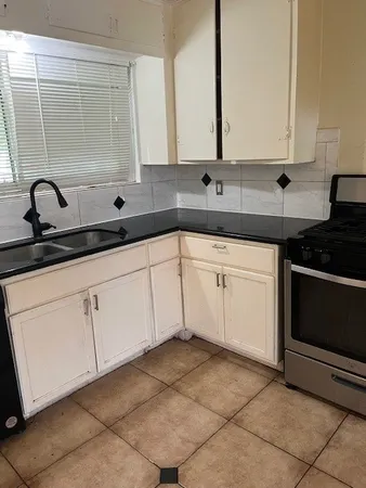 a kitchen with white cabinets and sink