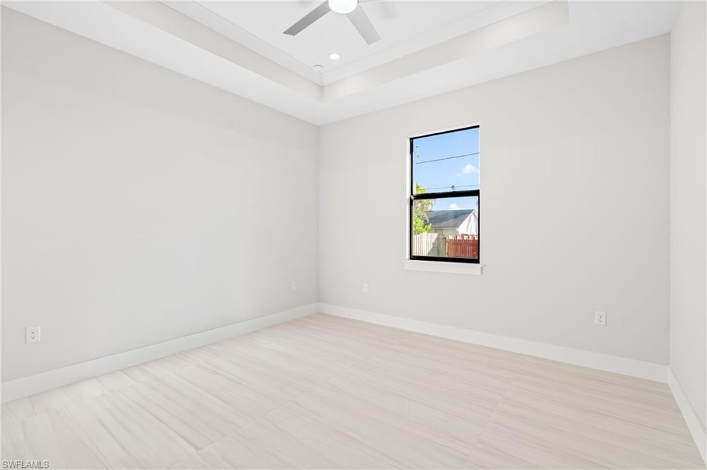 2064 55th Terrace Southwest Naples, FL 34116 - Photo 13 of 30 Spare room featuring a tray ceiling, a ceiling fan, and light floors