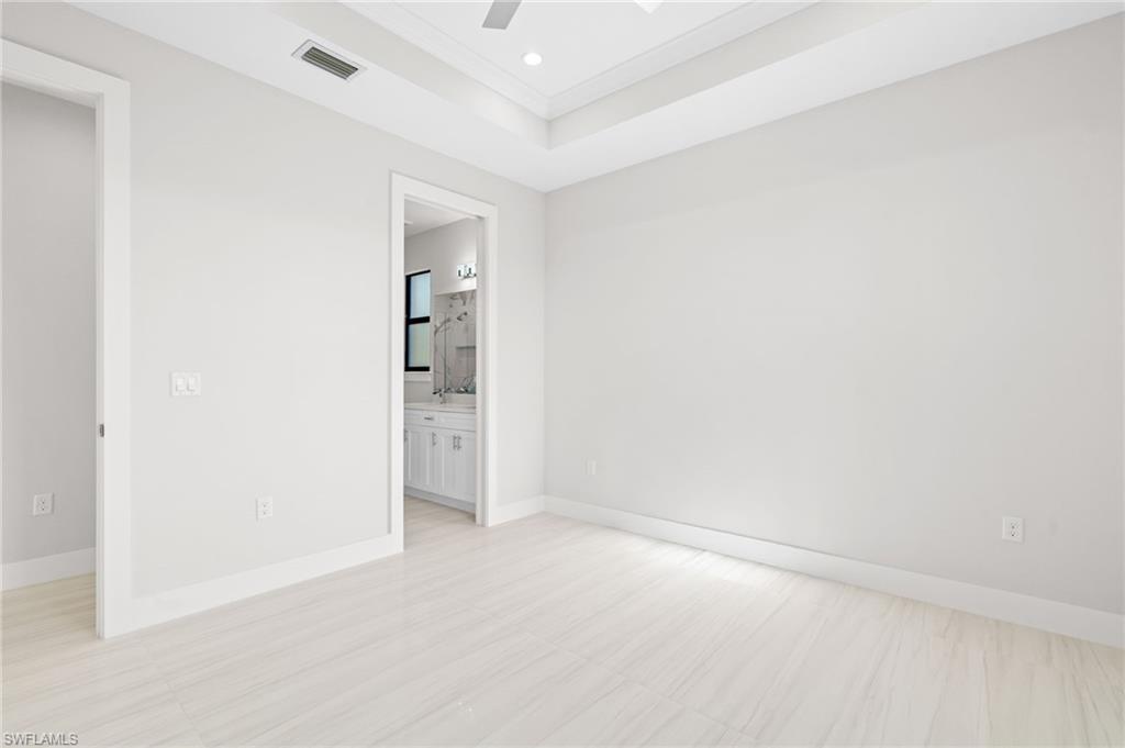 2064 55th Terrace Southwest Naples, FL 34116 - Photo 14 of 30 Unfurnished bedroom with ceiling fan, a raised ceiling, ensuite bathroom, crown molding, and recessed lighting