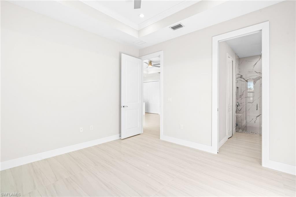 2064 55th Terrace Southwest Naples, FL 34116 - Photo 15 of 30 Unfurnished bedroom featuring a ceiling fan, a raised ceiling, connected bathroom, and recessed lighting
