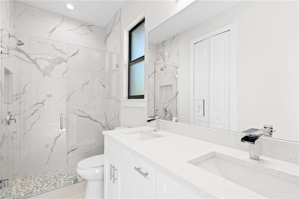 2064 55th Terrace Southwest Naples, FL 34116 - Photo 17 of 30 Full bathroom featuring double vanity, a marble finish shower, and a closet