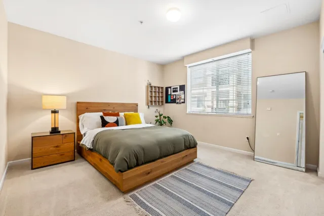 a bedroom with a bed lamp and a large window