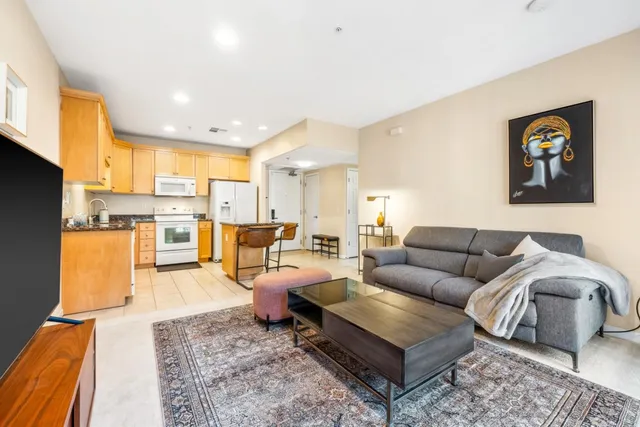a living room with furniture kitchen view and a large window
