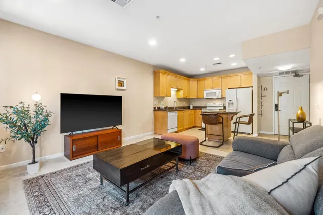 a living room with furniture kitchen view and a large window