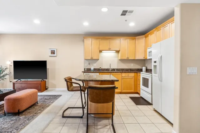 a kitchen with granite countertop a stove a sink and a refrigerator