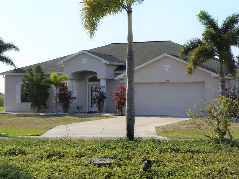 a view of a house with a yard and potted plants