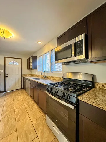 a kitchen with stainless steel appliances granite countertop a stove a sink and a microwave