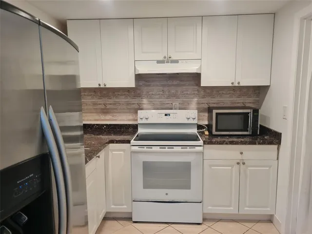 a kitchen with granite countertop white cabinets and white appliances