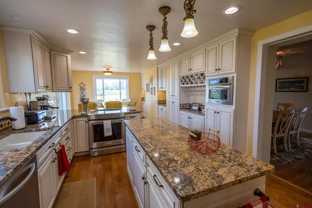 a large kitchen with kitchen island a large counter top stainless steel appliances and cabinets