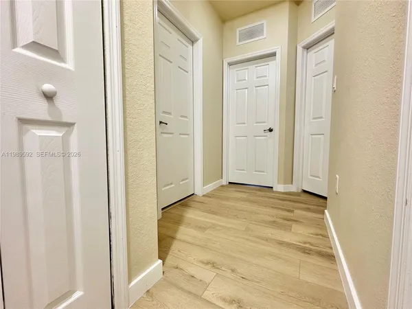 a view of a hallway with wooden floor and windows