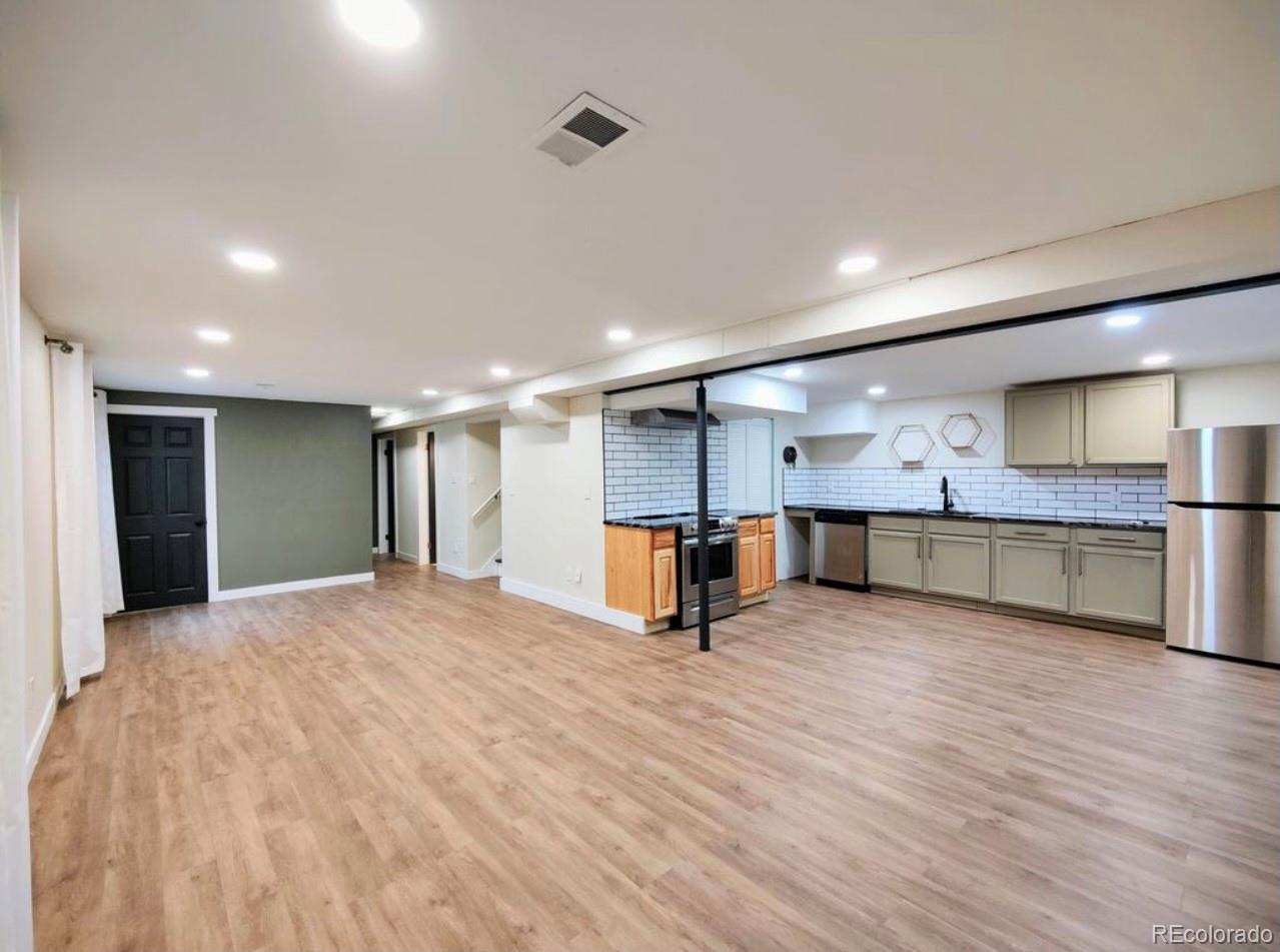 7770 South Kit Carson Drive Centennial, CO 80122 - Photo 14 of 30 a view of an empty room with wooden floor and a kitchen