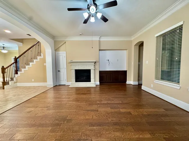 a view of an empty room with chandelier fan and fire place