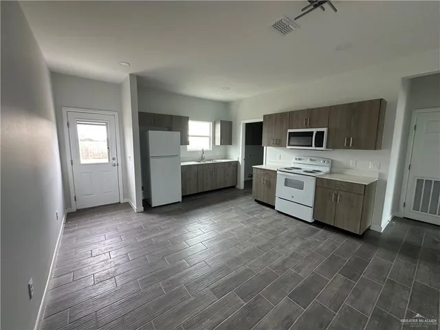 a view of a kitchen with a sink stove cabinets and empty room