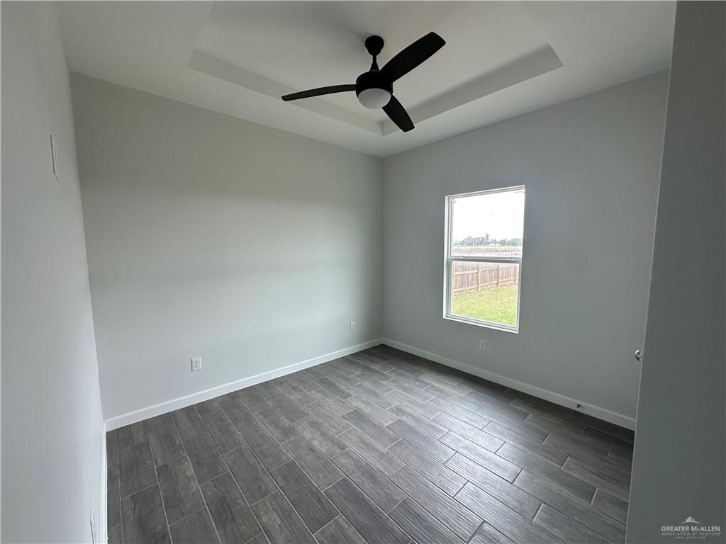 1704 Unity Drive Mercedes, TX 78570 - Photo 10 of 11 an empty room with wooden floor ceiling fan and windows