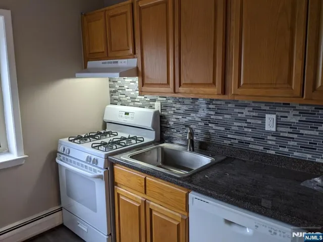 a kitchen with granite countertop a sink stove and cabinets