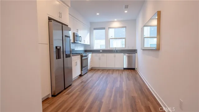 a large kitchen with a wooden floor and stainless steel appliances