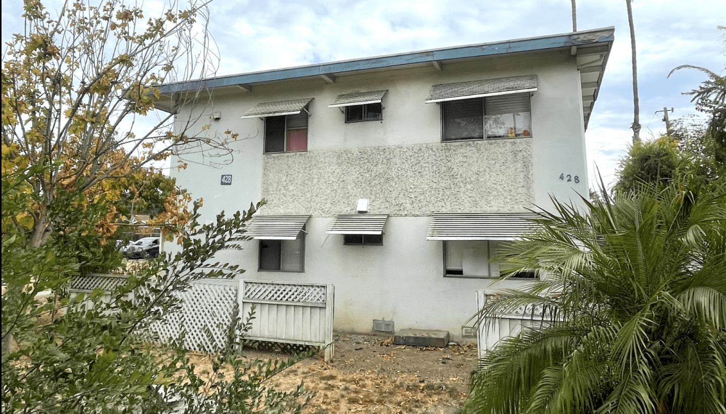 a front view of a house with a tree