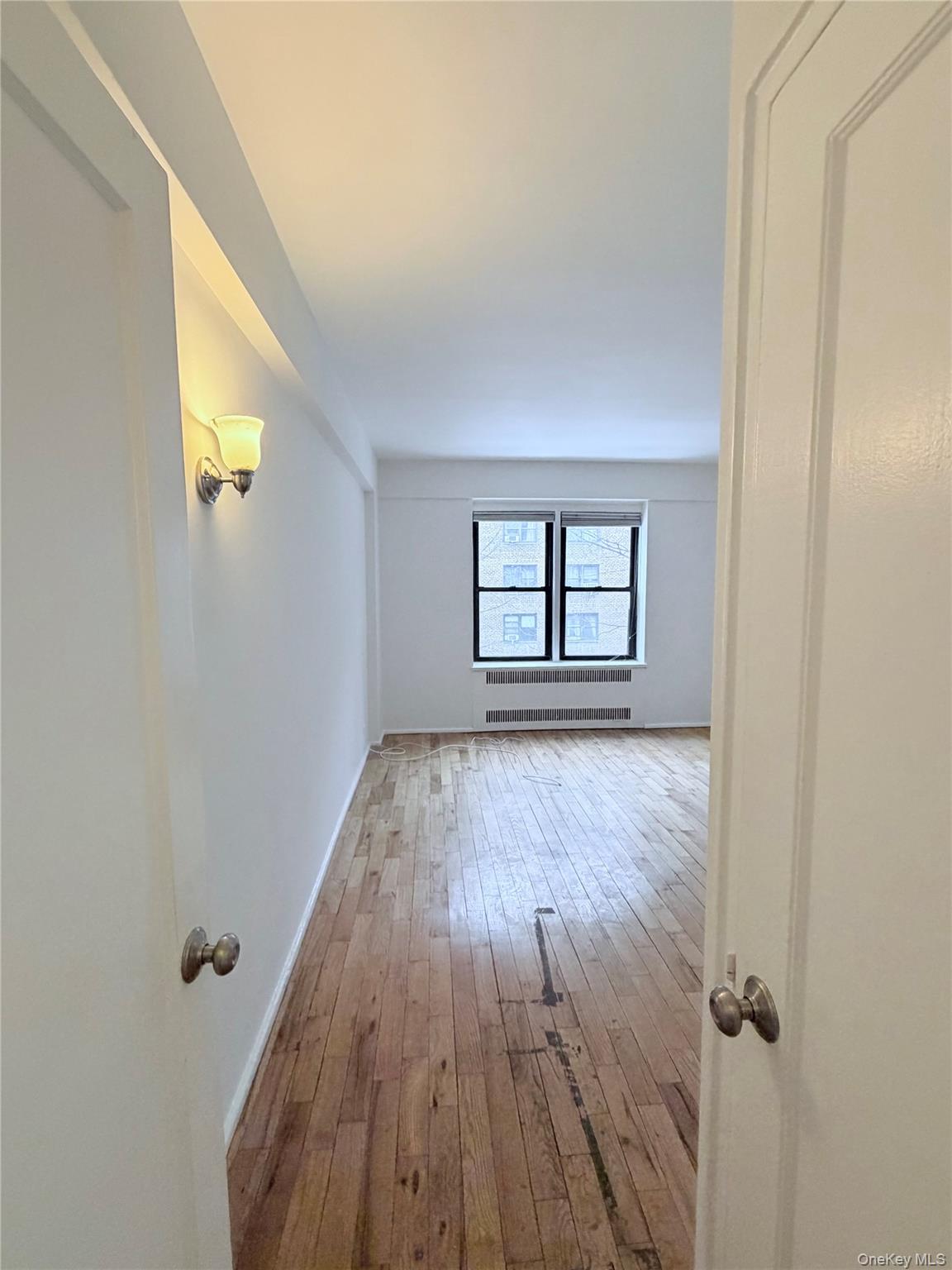 99-21 67th Road, Unit 3A Queens, NY 11375 - Photo 11 of 18 bedroom featuring light wood-style flooring and radiator heating unit