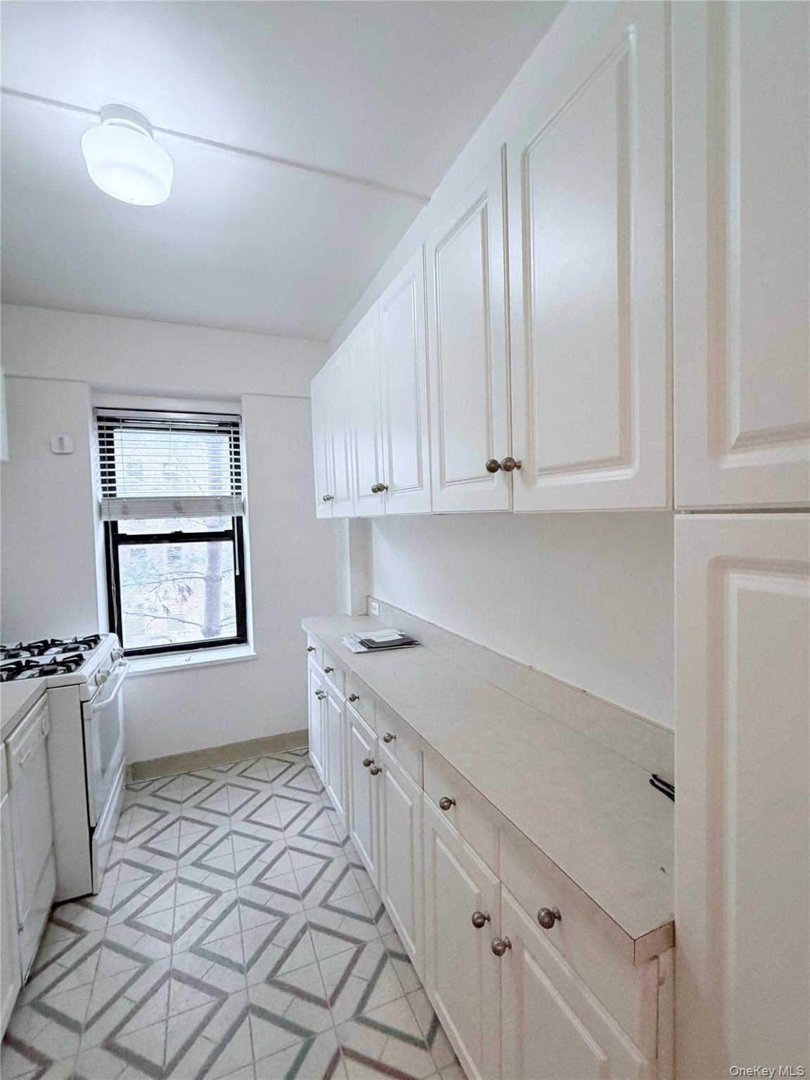 99-21 67th Road, Unit 3A Queens, NY 11375 - Photo 12 of 22 a kitchen with granite countertop white cabinets and appliances