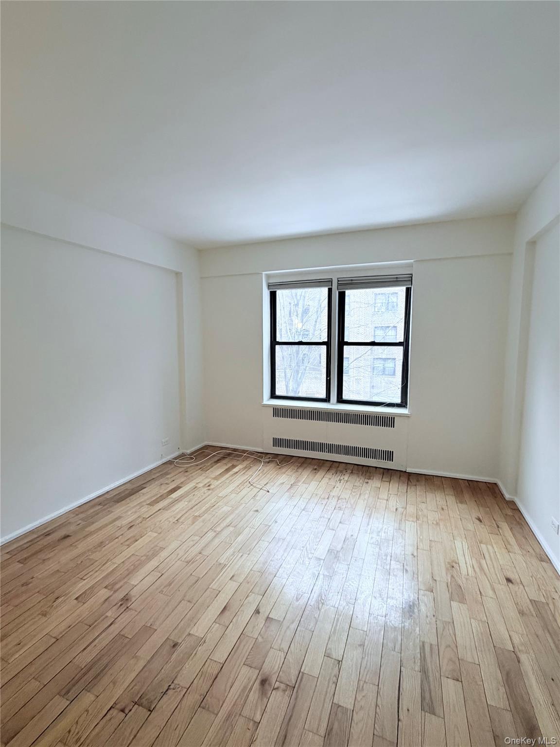 99-21 67th Road, Unit 3A Queens, NY 11375 - Photo 17 of 22 an empty room with wooden floor and windows