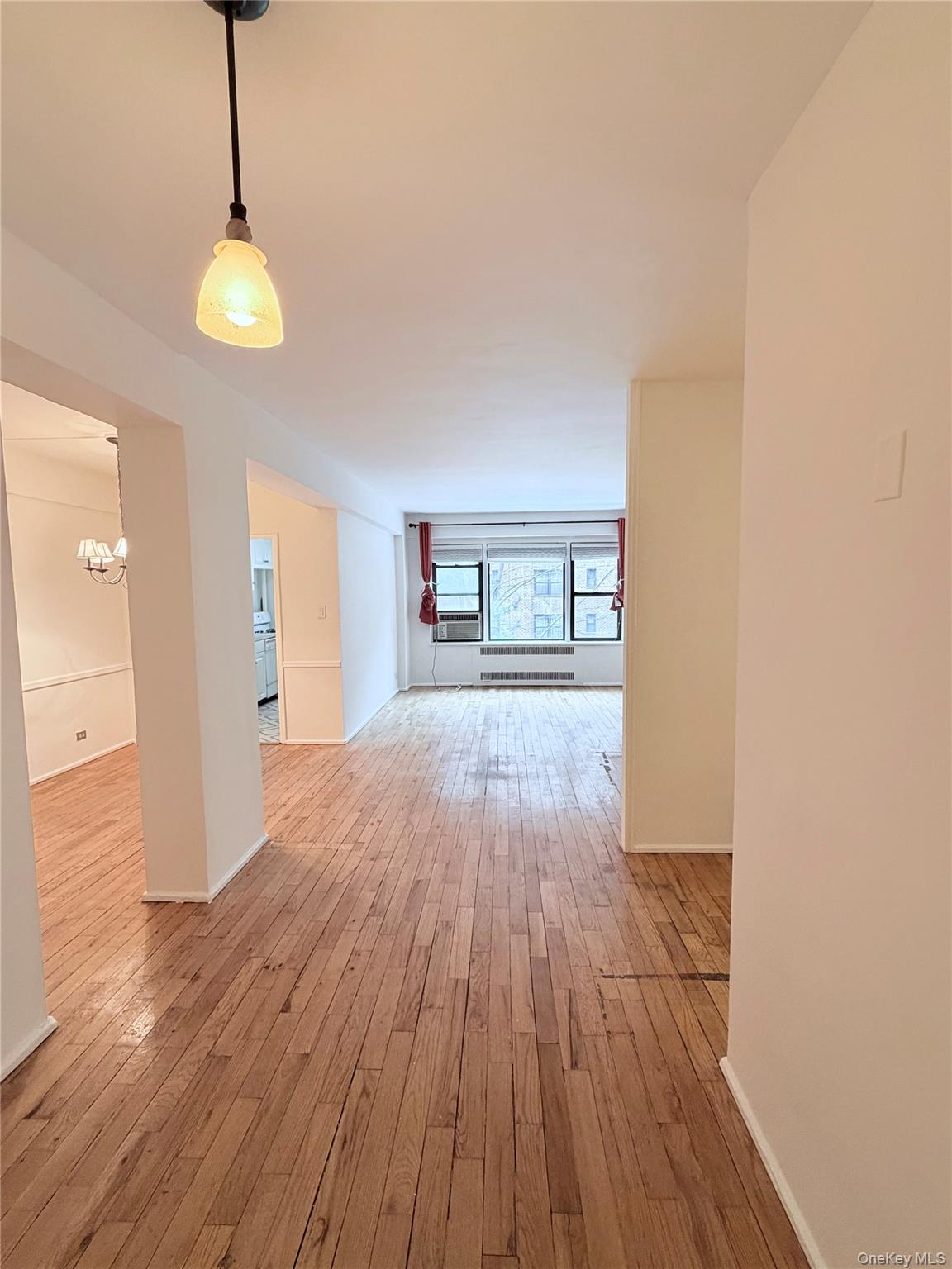 99-21 67th Road, Unit 3A Queens, NY 11375 - Photo 5 of 22 a view of an empty room with wooden floor and a window