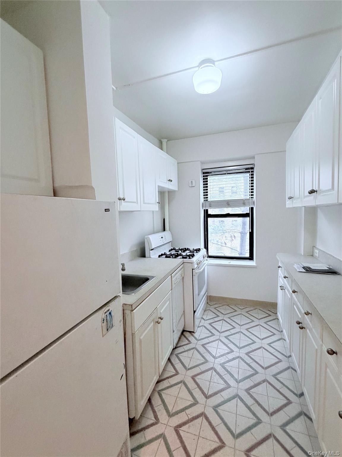 99-21 67th Road, Unit 3A Queens, NY 11375 - Photo 8 of 18 Kitchen featuring white appliances, light countertops, and white cabinetry
