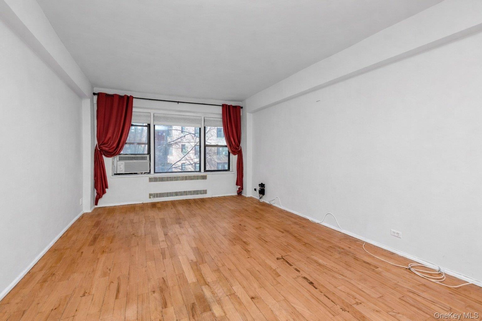 99-21 67th Road, Unit 3A Queens, NY 11375 - Photo 10 of 22 an empty room with wooden floor and windows