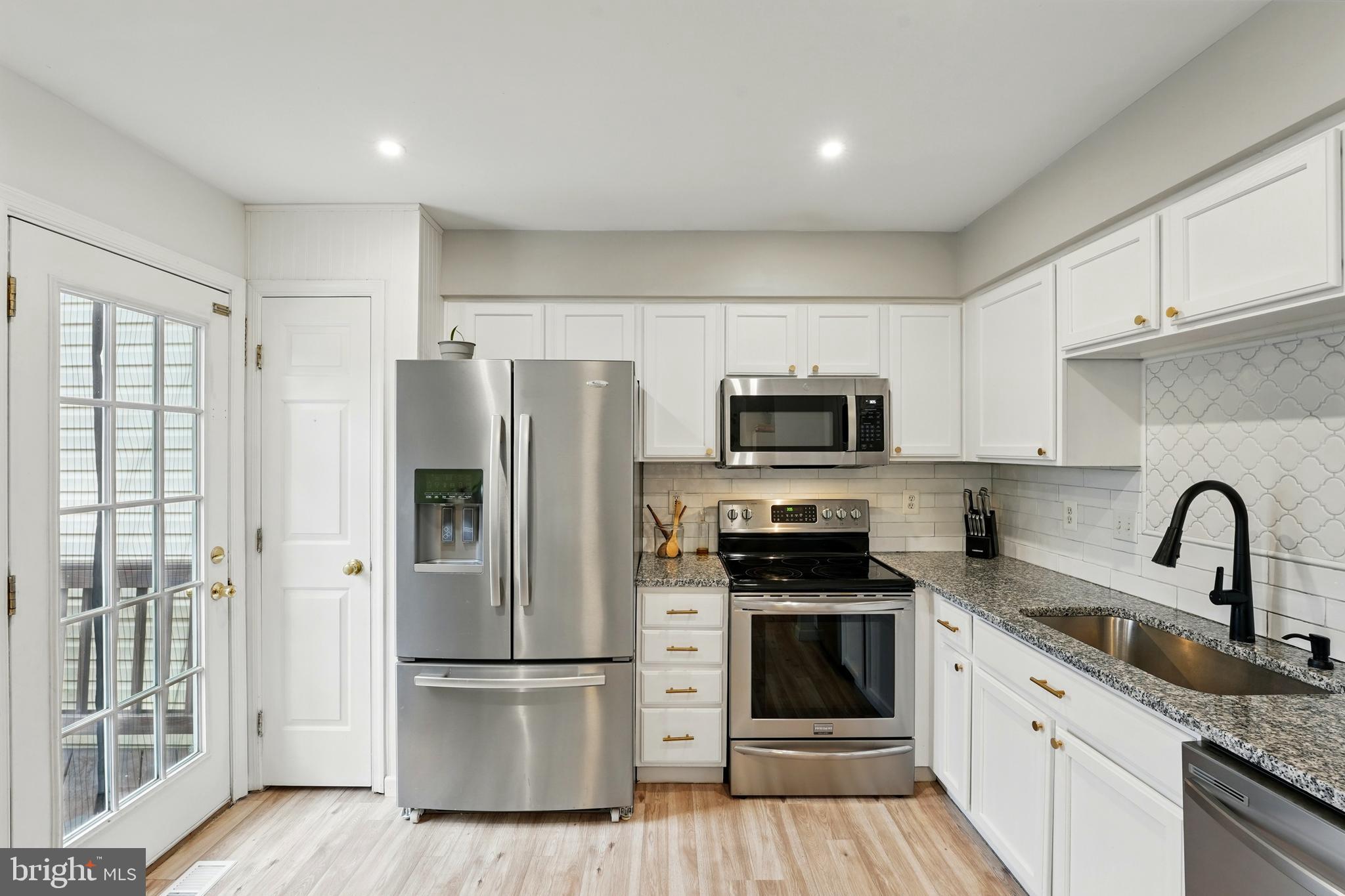 7045 Sauvage Lane Gainesville, VA 20155 - Photo 17 of 43 a kitchen with stainless steel appliances granite countertop a refrigerator stove and white cabinets
