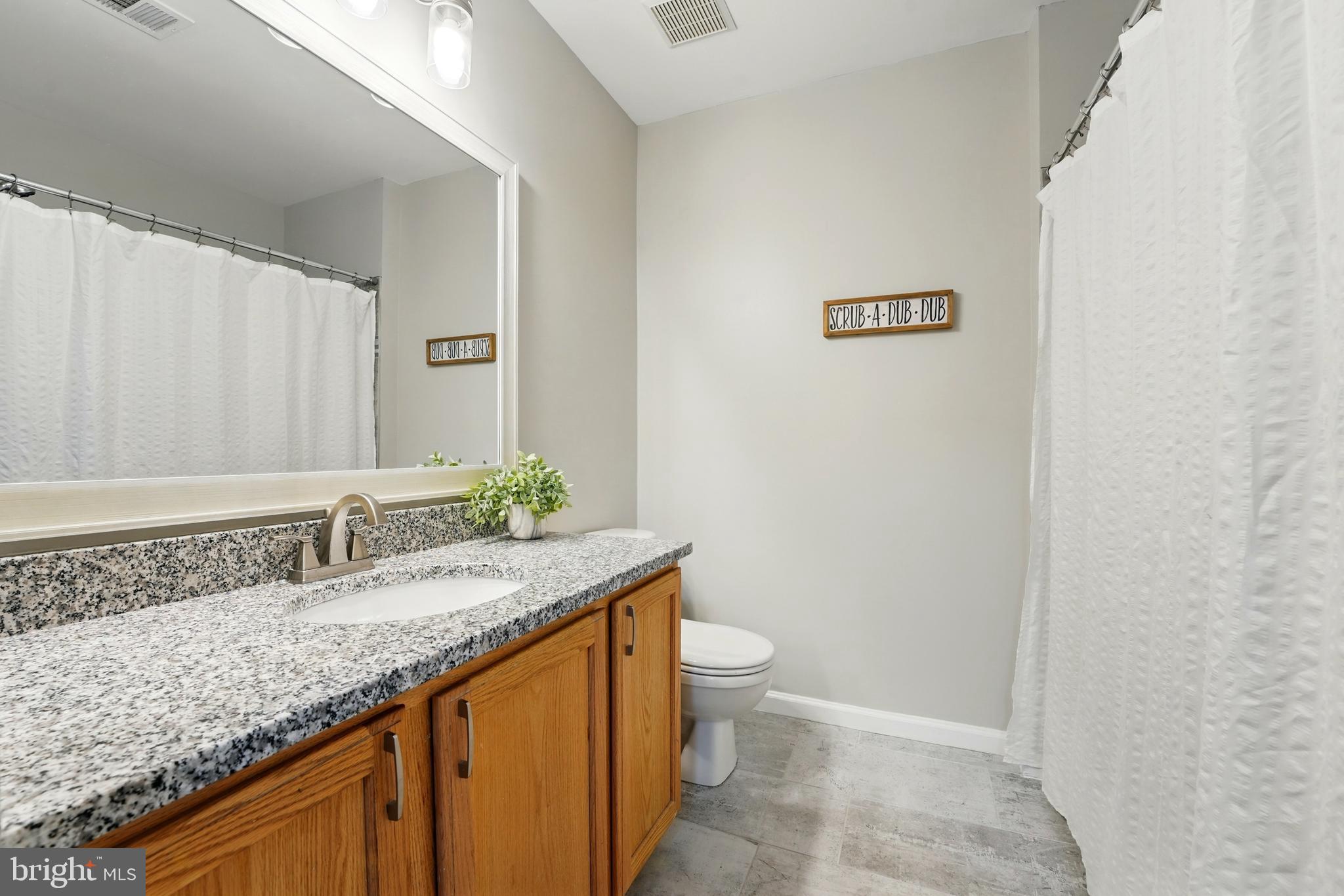 7045 Sauvage Lane Gainesville, VA 20155 - Photo 23 of 43 a bathroom with a granite countertop sink a toilet and a mirror