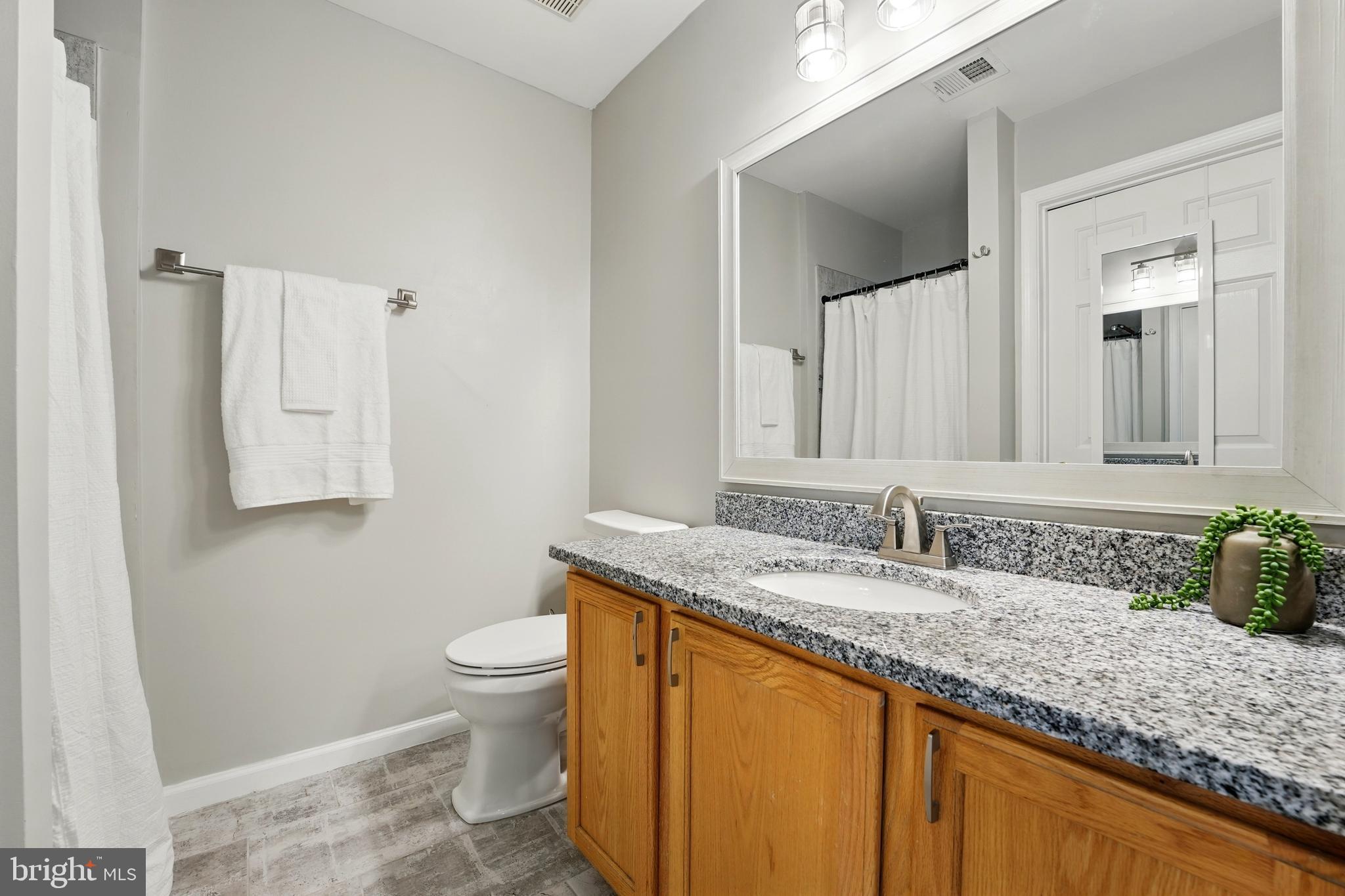 7045 Sauvage Lane Gainesville, VA 20155 - Photo 31 of 43 a bathroom with a granite countertop sink a toilet and a mirror