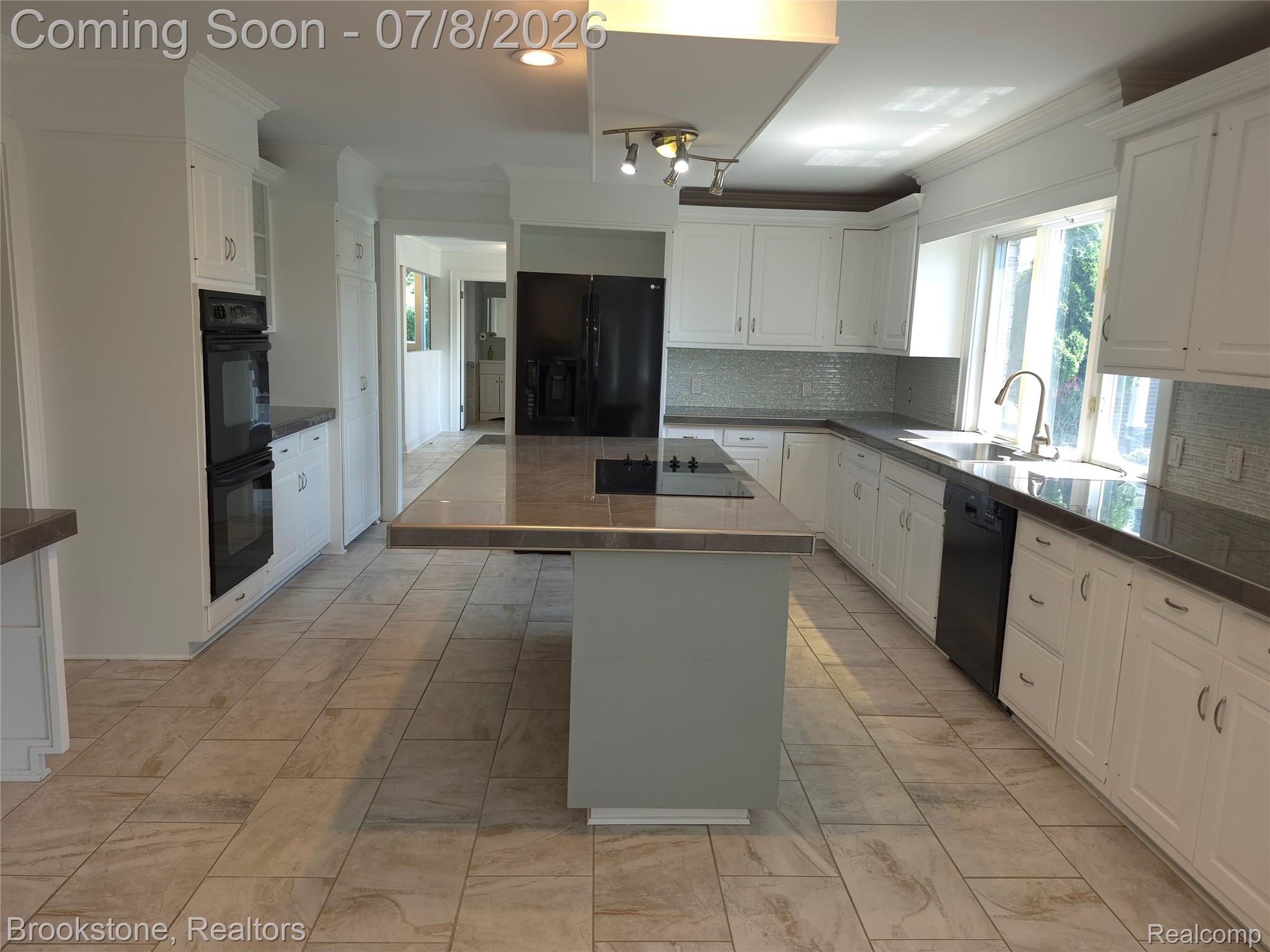 4140 South Henderson Road Davison, MI 48423 - Photo 21 of 98 Expansive kitchen featuring a central island with cooktop, white cabinetry, integrated double wall ovens, a tile backsplash, and a large window above the sink