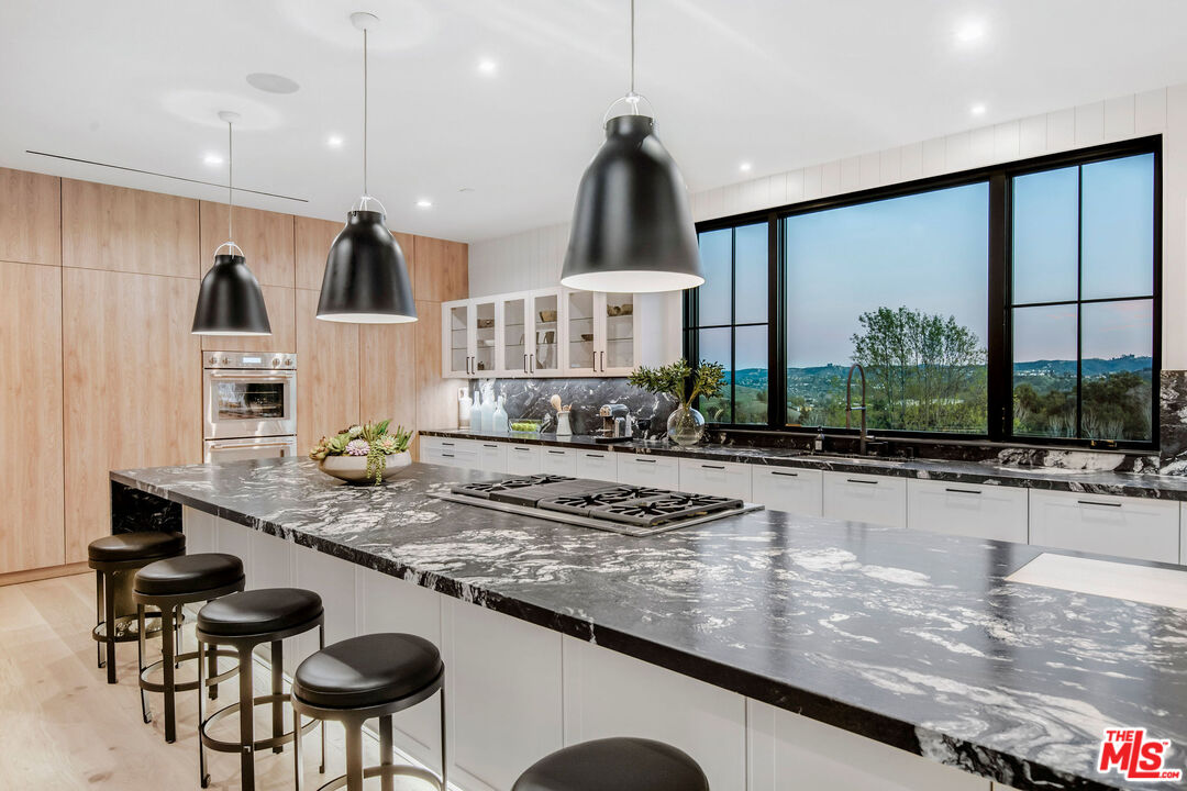 5505 Hoback Glen Road Hidden Hills, CA 91302 - Photo 22 of 43 a kitchen with stainless steel appliances granite countertop a stove a sink and a dining table with the view of living room