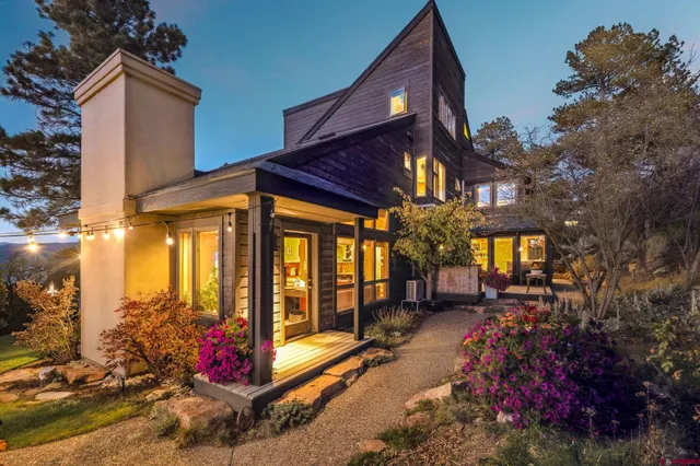 a view of a house with large windows and flower plants