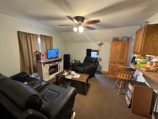 a work room with furniture a ceiling fan and a window