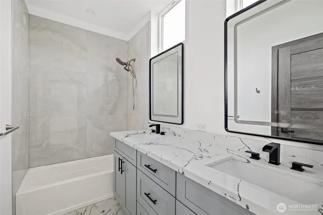 a bathroom with a sink double vanity granite tub shower and a mirror