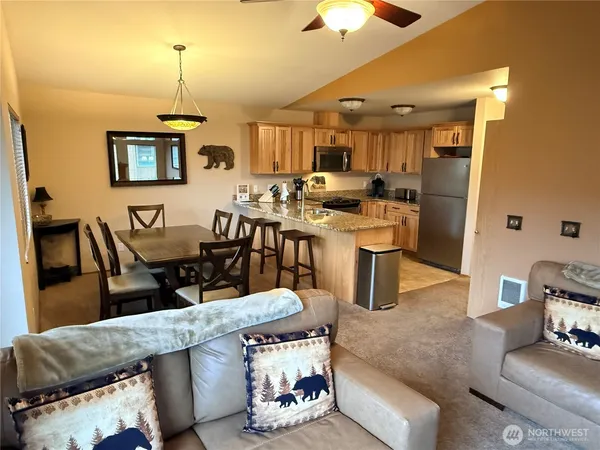 a living room with stainless steel appliances kitchen island granite countertop furniture and a chandelier