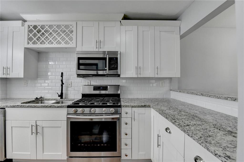 516 Wynnes Ridge Circle Southeast, Unit 516 Marietta, GA 30067 - Photo 18 of 40 a kitchen with granite countertop a stove a microwave a sink and cabinets