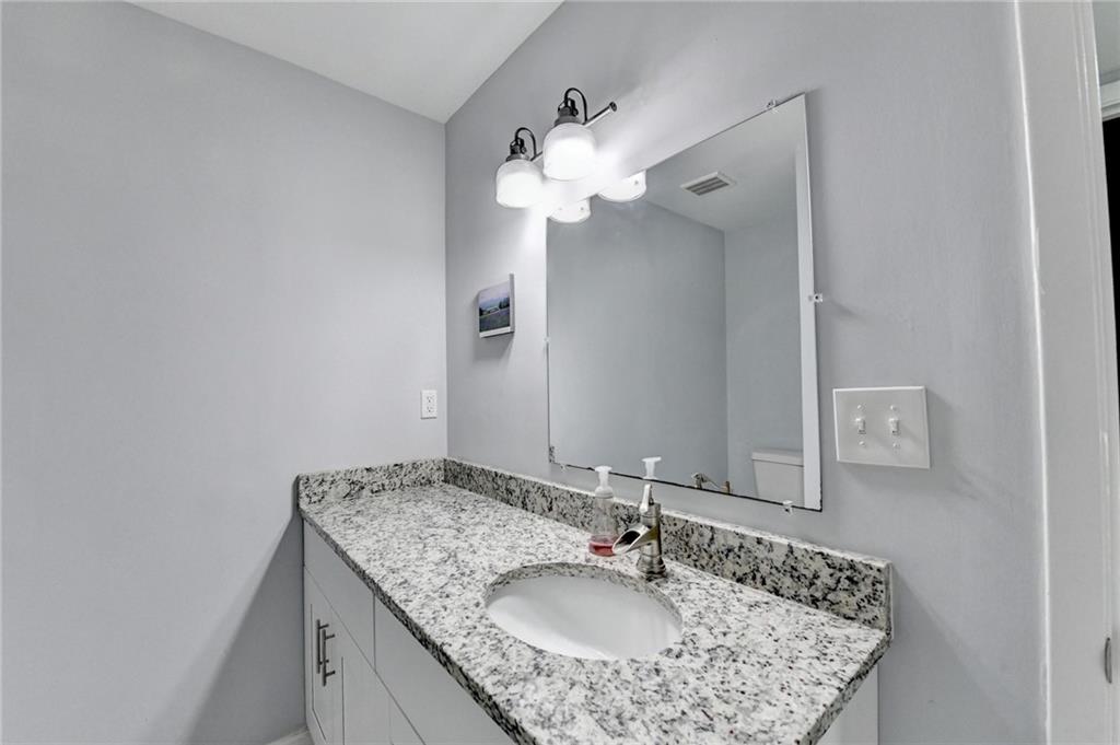 516 Wynnes Ridge Circle Southeast, Unit 516 Marietta, GA 30067 - Photo 28 of 40 a bathroom with a granite countertop sink a mirror and a light fixture