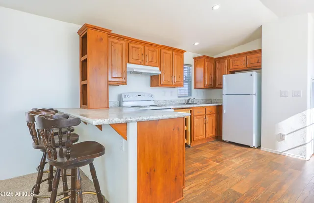 a kitchen with stainless steel appliances granite countertop a sink refrigerator and cabinets