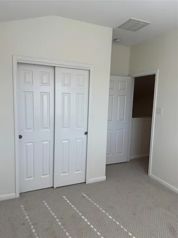 a view of an empty room with closet and wooden floor