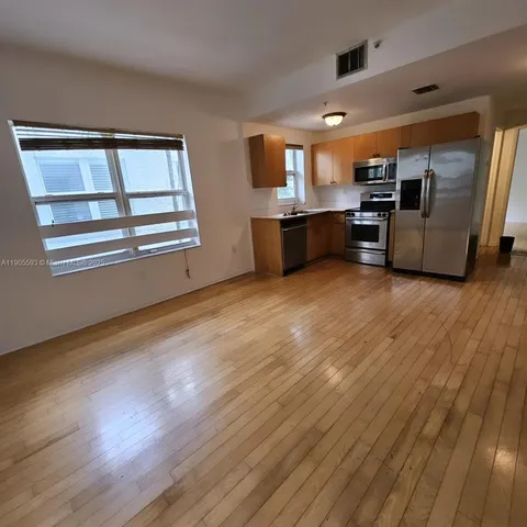 a view of kitchen with kitchen island wooden floor and stainless steel appliances