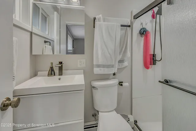a white toilet sitting next to a white sink and a shower