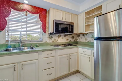 a kitchen with white cabinets and refrigerator