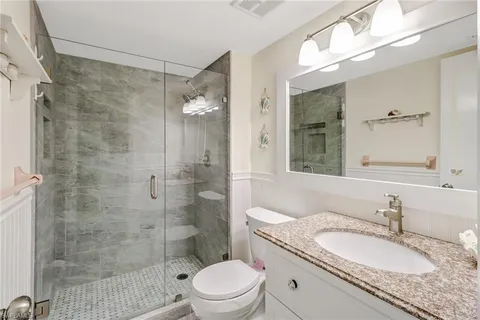 a bathroom with a granite countertop sink toilet a mirror a shower and a bathtub
