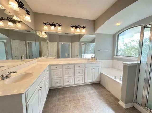 a spacious bathroom with a double vanity sink a large mirror and a bathtub