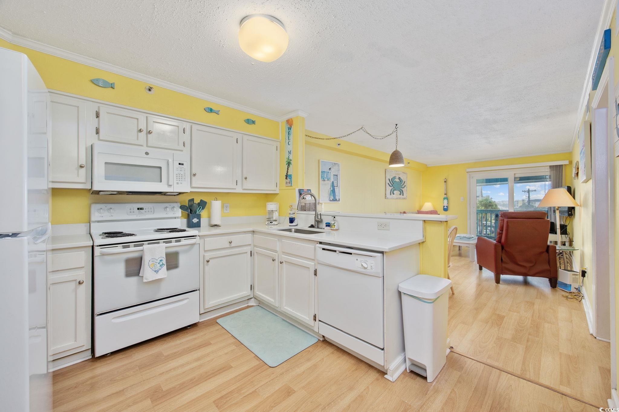 720 North Waccamaw Drive, Unit 301 Murrells Inlet, SC 29576 - Photo 3 of 37 Kitchen featuring a peninsula, white appliances, a textured ceiling, light countertops, and white cabinetry