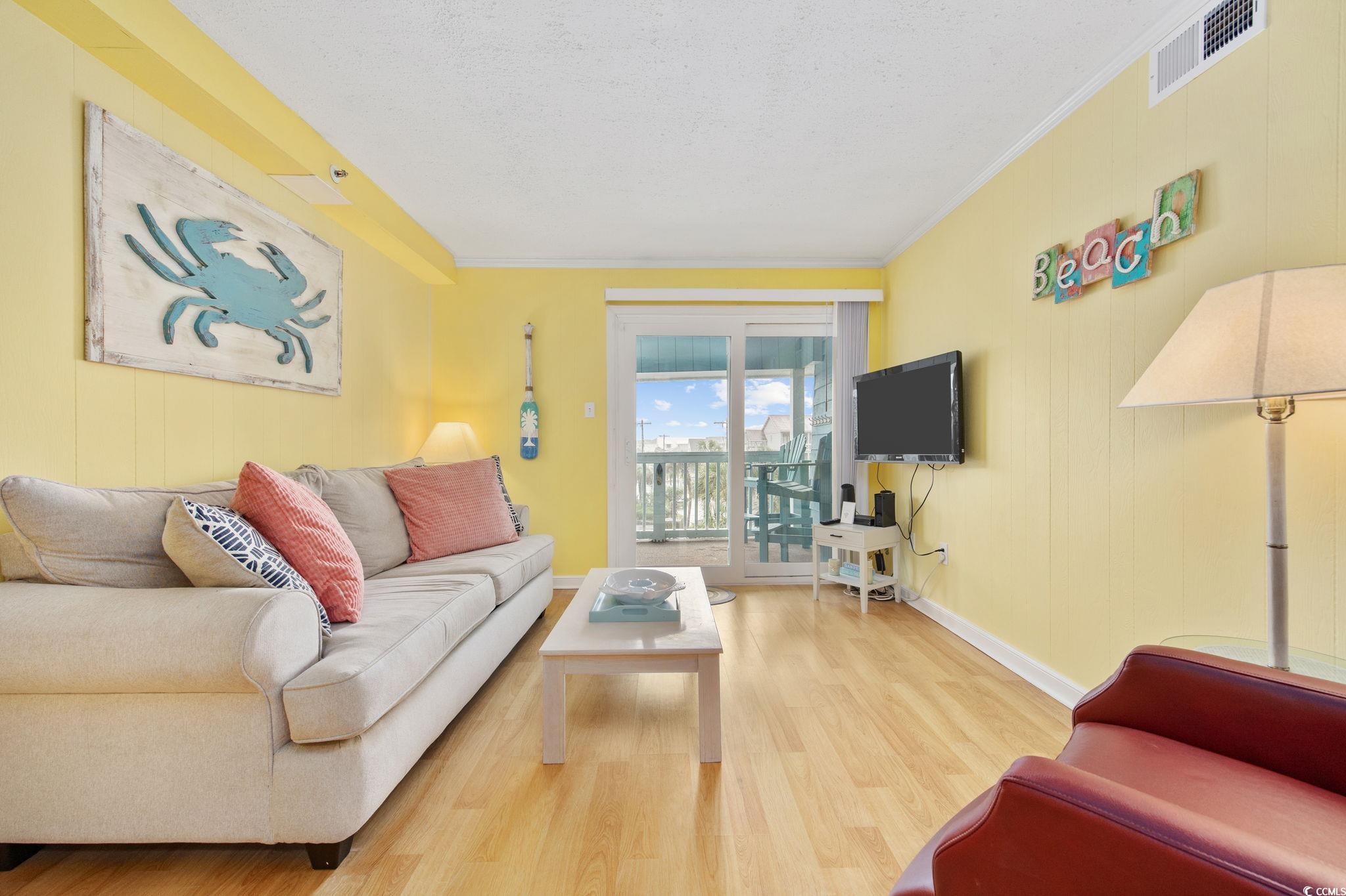 720 North Waccamaw Drive, Unit 301 Murrells Inlet, SC 29576 - Photo 9 of 37 Living area featuring wood finished floors, ornamental molding, wood walls, and a textured ceiling