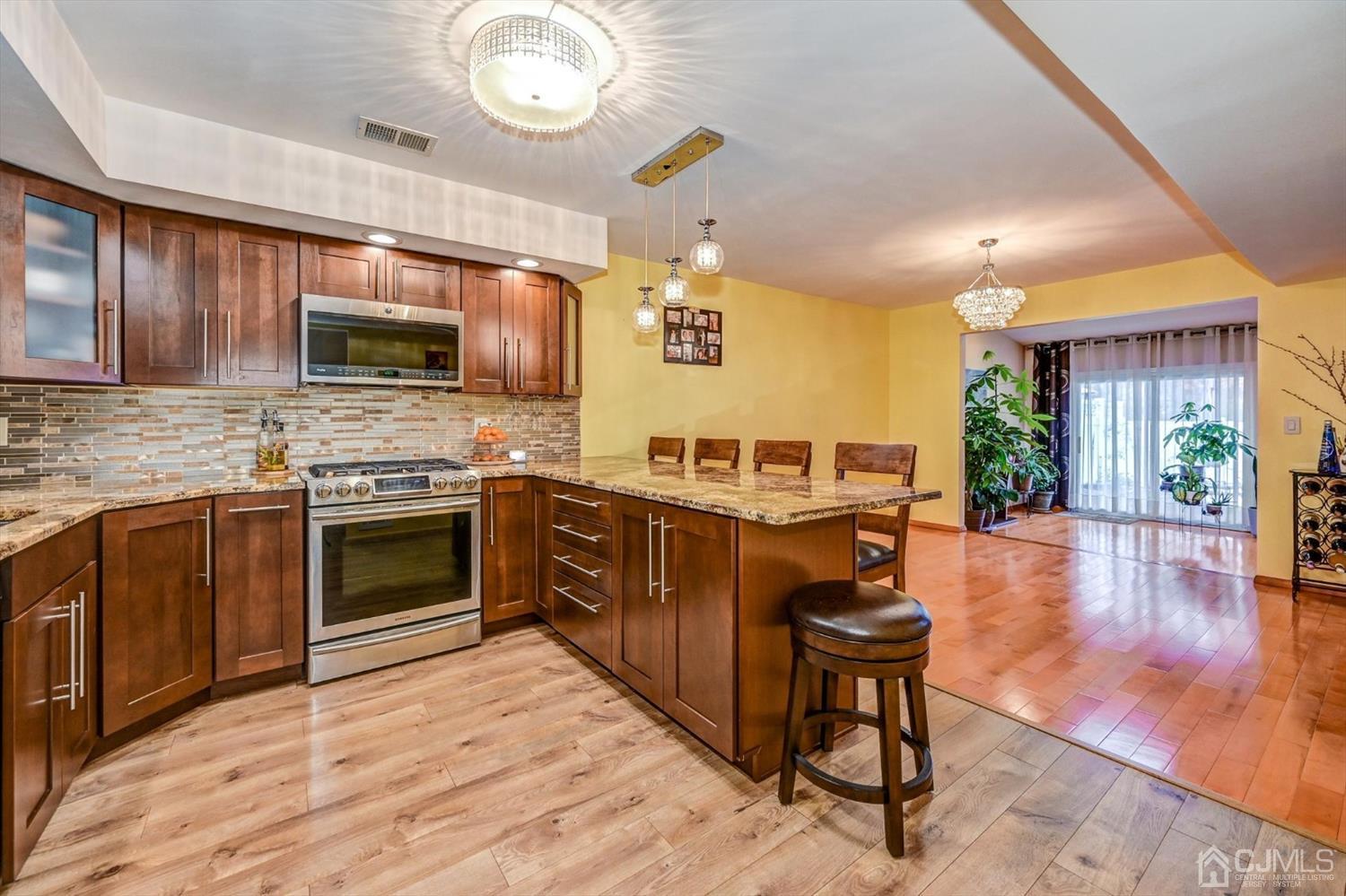 136 Redpine Loop Old Bridge, NJ 08857 - Photo 8 of 31 a kitchen with stainless steel appliances granite countertop a stove top oven a sink dishwasher a dining table and chairs with wooden floor