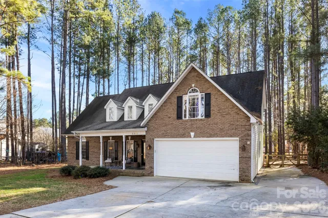 a front view of a house with a garden and trees