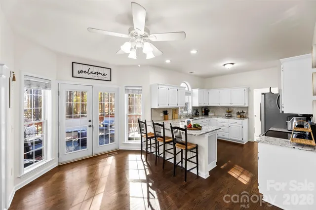 a view of kitchen with stainless steel appliances kitchen island granite countertop a refrigerator a stove a dining table and chairs with wooden floor